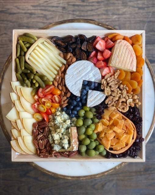 Image of the Farmstead Cheese Platter, very colorful mix of fresh fruits, olives, and nuts surrounding chipped, wedges, and quartered cheeses.