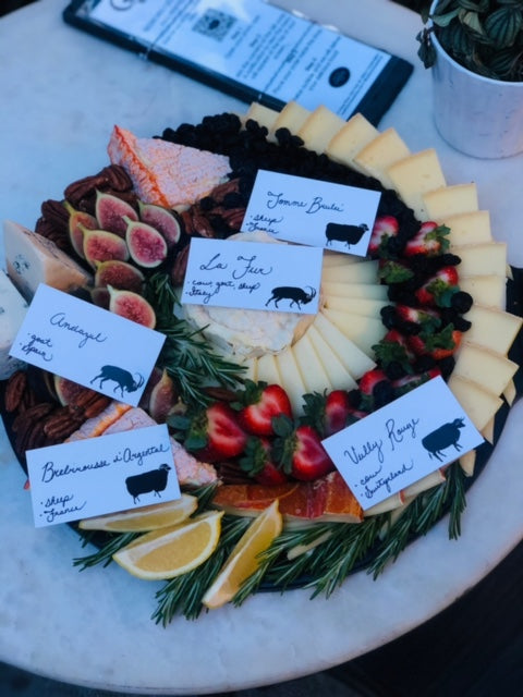 Image of a special holiday cheese board made for a private event. Assorted wedged cheese slices and rosemary creating a colorful wreath design.