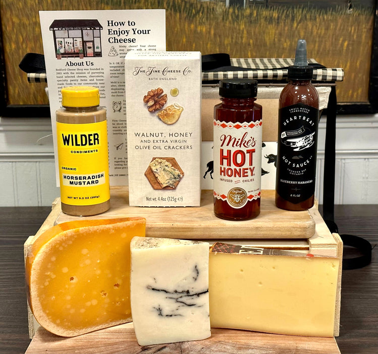Image of the Washington Square Park gift basket contents. Includes: hot honey, mustard, hot sauce, crackers, assorted cheeses, and a card.