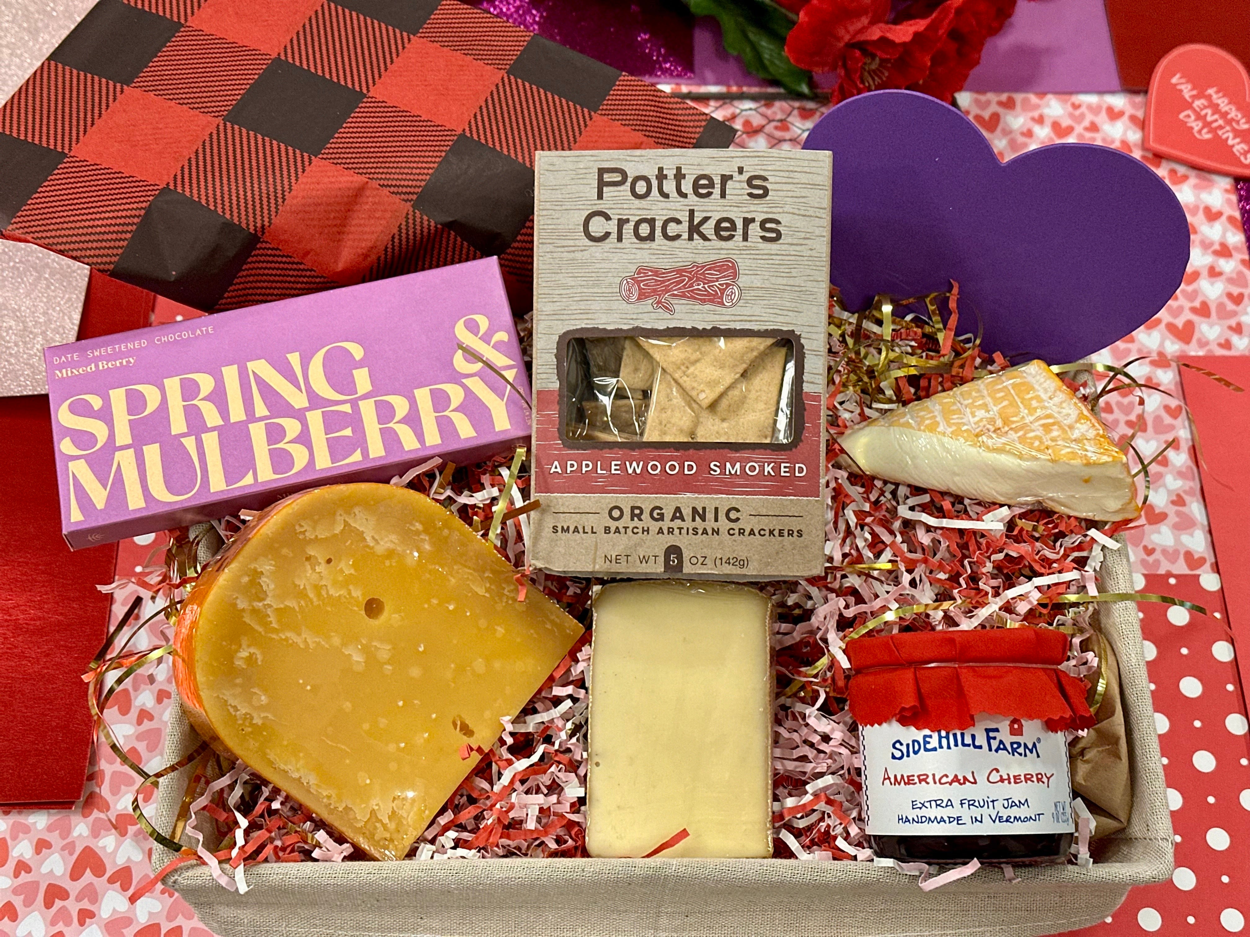 Image of our valentine's day basket taken from above including cheeses, chocolate, crackers, and jam.