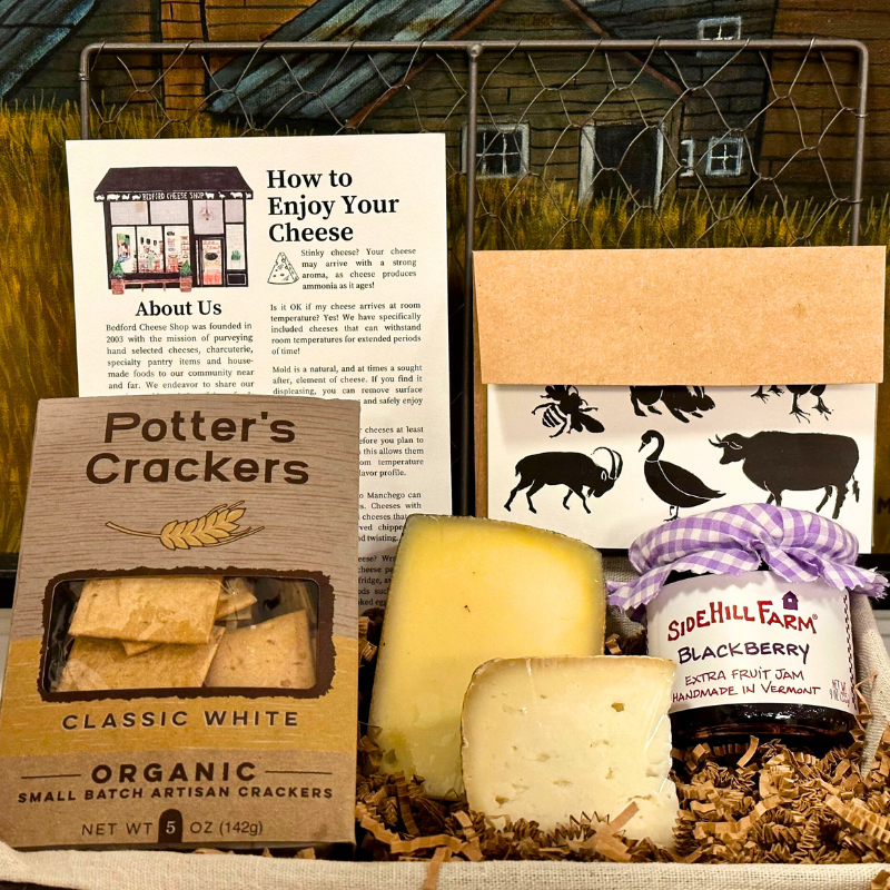 Image is of an open Gramercy Park gift basket. Includes cheeses, jam, crackers, and a card, 