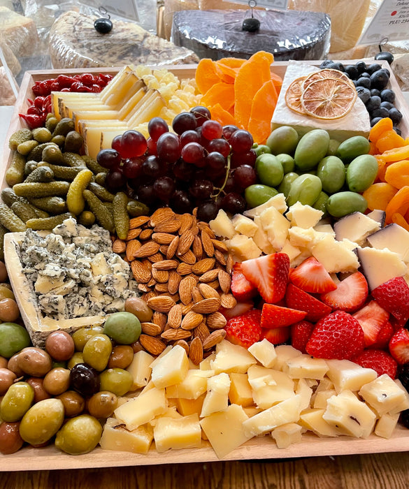 Image is a side view of the Signature Cheese Platter with olives, nuts, fresh and dried fruit and additional accoutrements. 