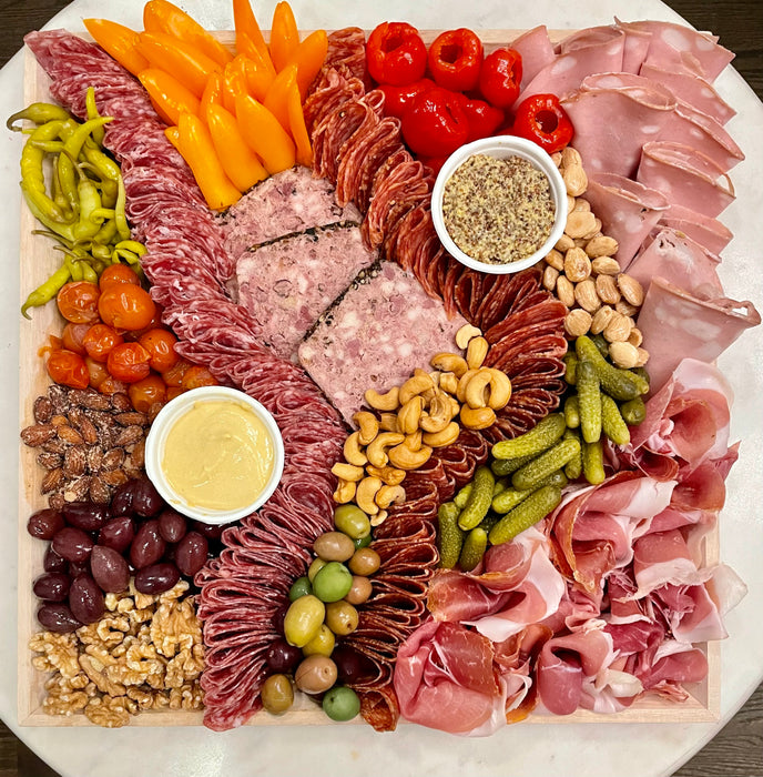 Image of large charcuterie platter (cured meats only, no cheese). Assorted cured meats served with nuts, assorted olives, cornichons, whole grain and smooth grain mustards. Pricing for small platters $133 large platter is $168 plus taxes and fees.